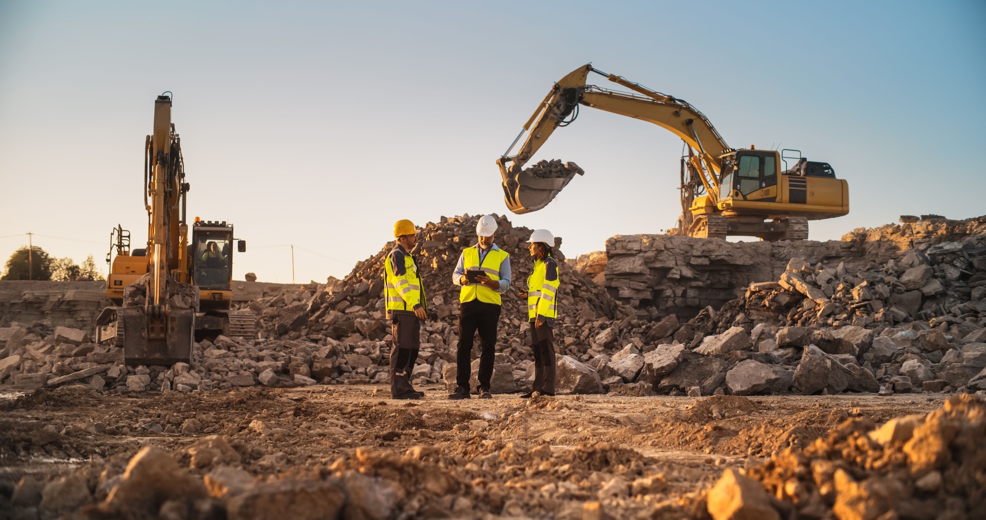 Construction Site With Excavators on Sunny Day: Diverse Team Of Male And Female Specialists Discussing Real Estate Project. Civil Engineer, Architect And Investor Talking About Apartment Building.