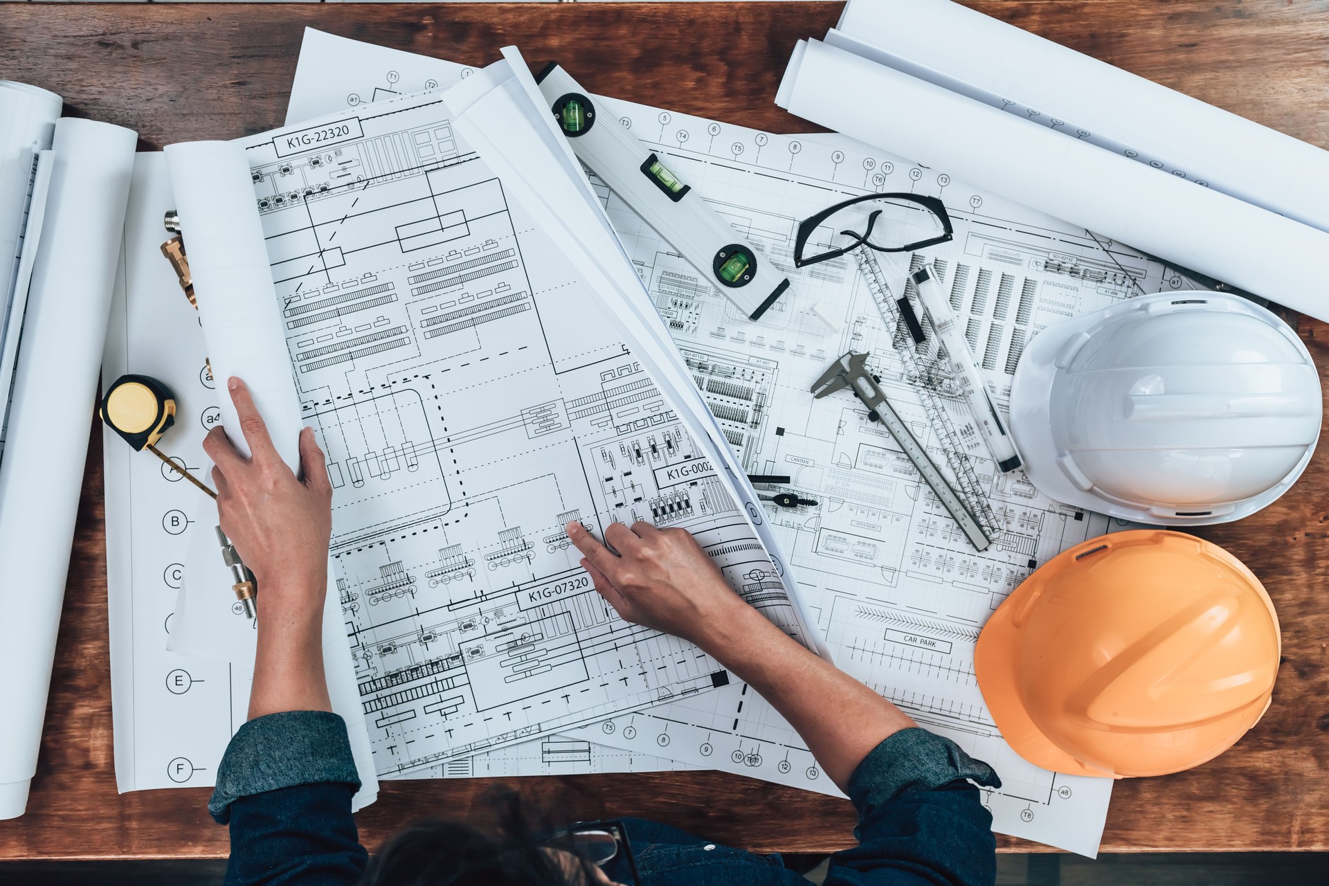 Top view Engineering working with drawings inspection on the office desk and Calculator, triangle ruler, safety glasses, compass, vernier caliper on Blueprint. Engineer, Architect, Industry and factory concept.